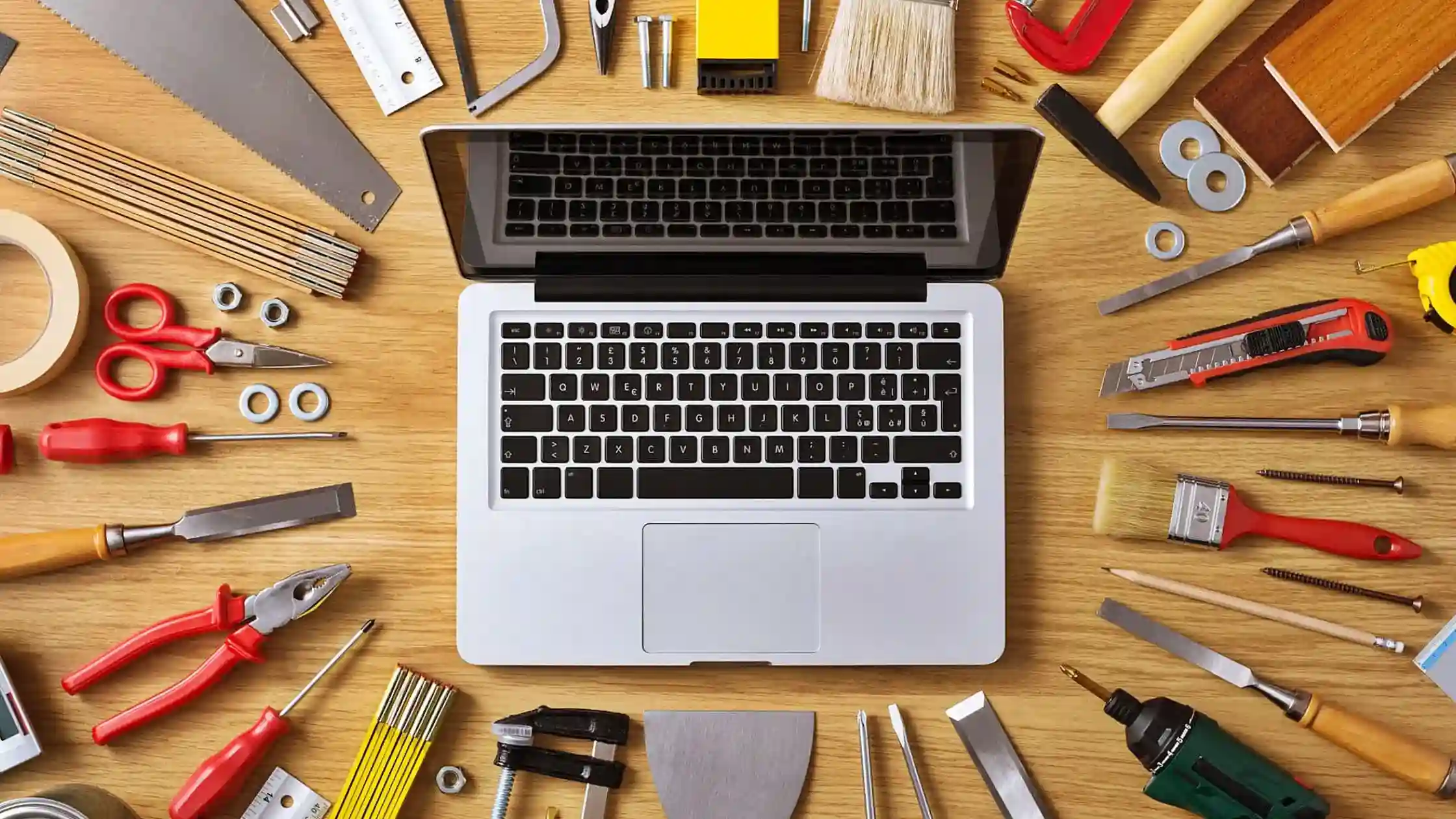 Laptop surrounded by a variety of DIY tools on a wooden surface